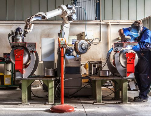 The mechanical performs welds metal components assisted by a worker.